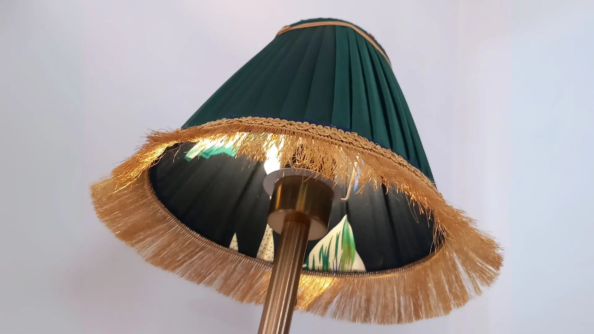 Abat-jour plissé vert avec franges dorées, réalisé dans le cadre d’une formation professionnelle en création d’abat-jour.