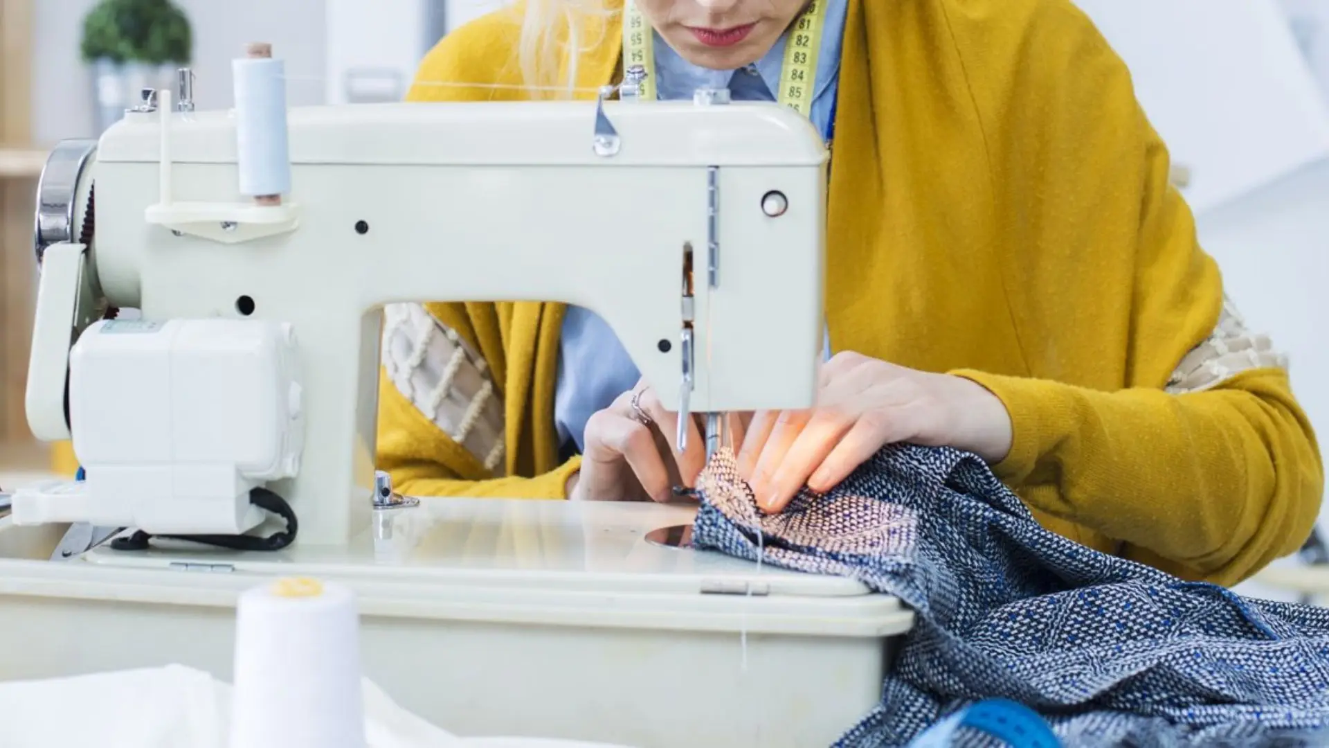Personne en formation couture travaillant sur une machine à coudre professionnelle, concentrée sur l’assemblage d’un tissu épais.